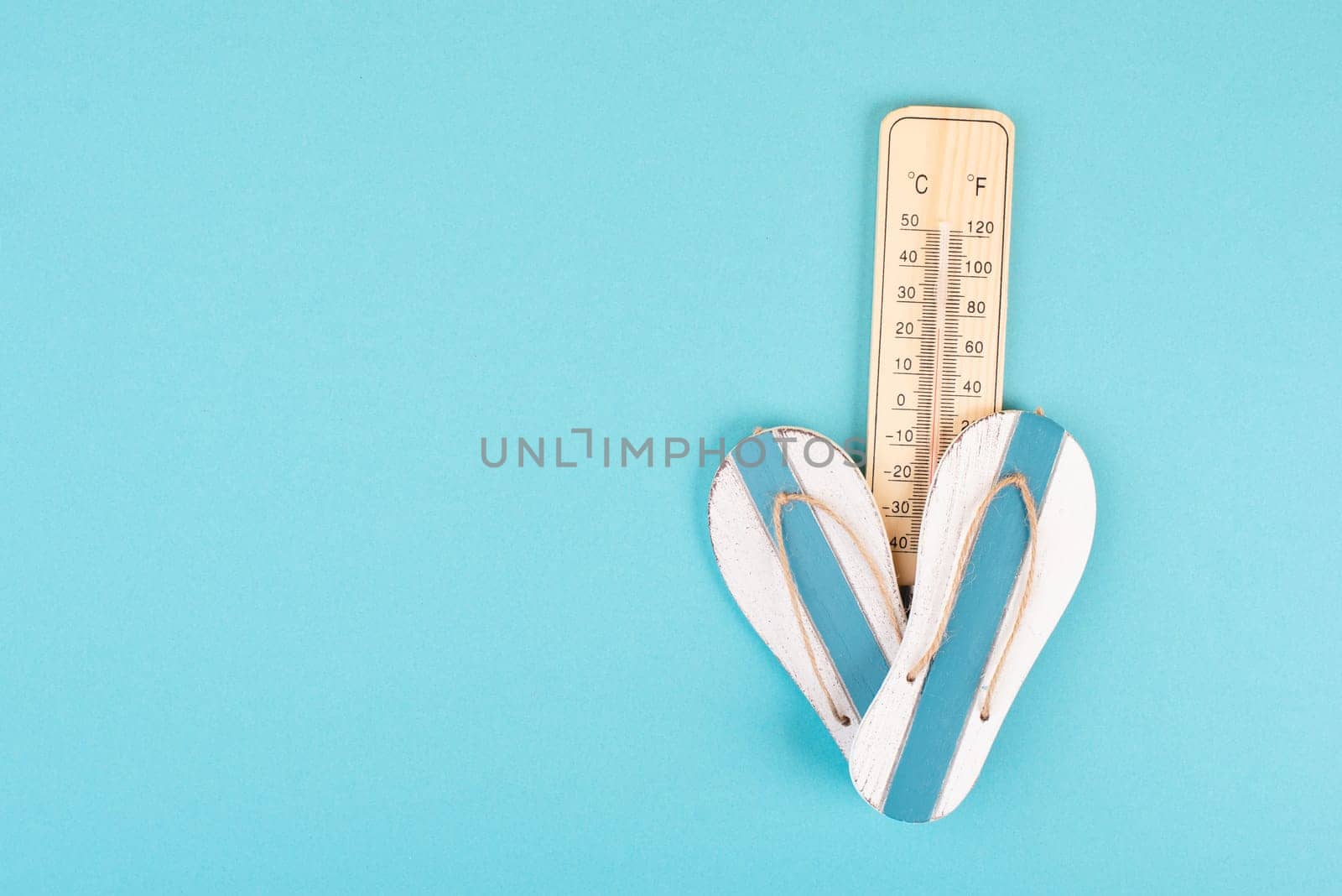 Empty blue background with a thermometer and flip flops, holiday background, summer vacation, hot weather, beach items