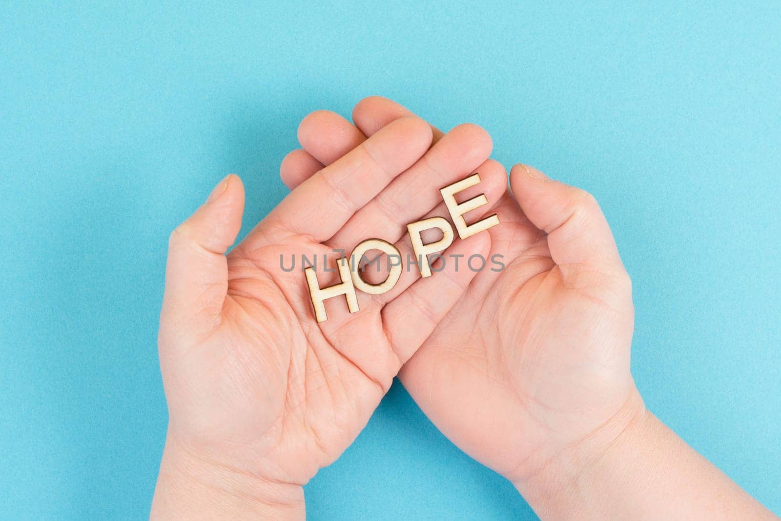 Holding the word hope in the palm of the hands, trust and believe concept, having faith in the future, hopeful positive mindset