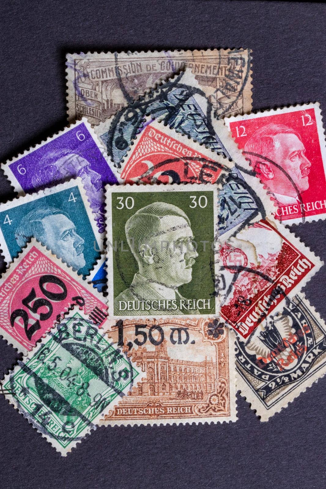 Potsdam, Germany - APR 26, 2022. A stack of old German stamps from the Third Reich and on it a stamp with printed portrait of Adolf Hitler, the leader of NSDAP party. Macro.
