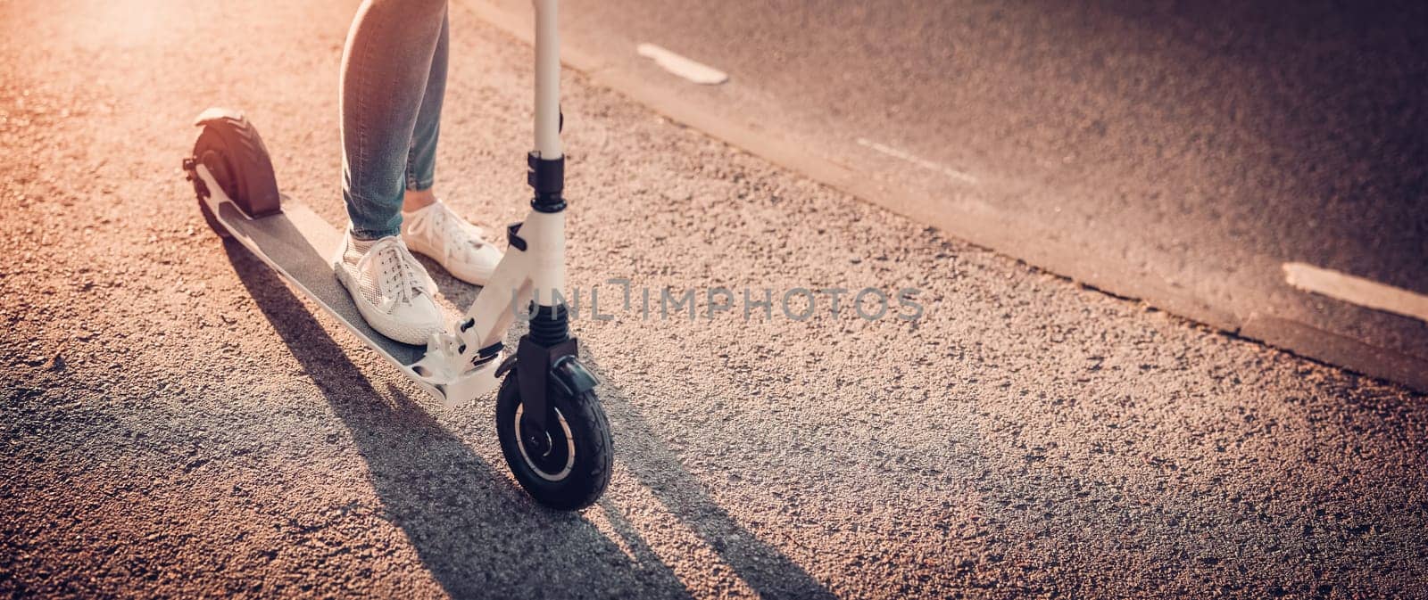 Woman riding on scooter on asphalt road in summer. Concept of city life.