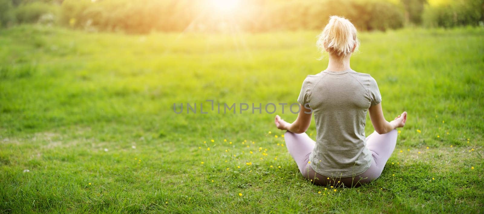 Woman sitting in active wear in lotus position in nature. Concept of healthy lifestyle.