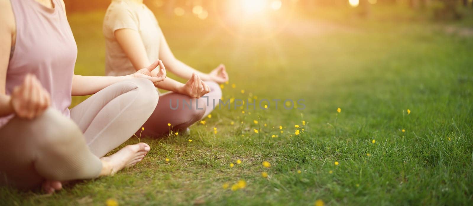 Two women sitting in active wear in lotus position in nature. Concept of healthy lifestyle.