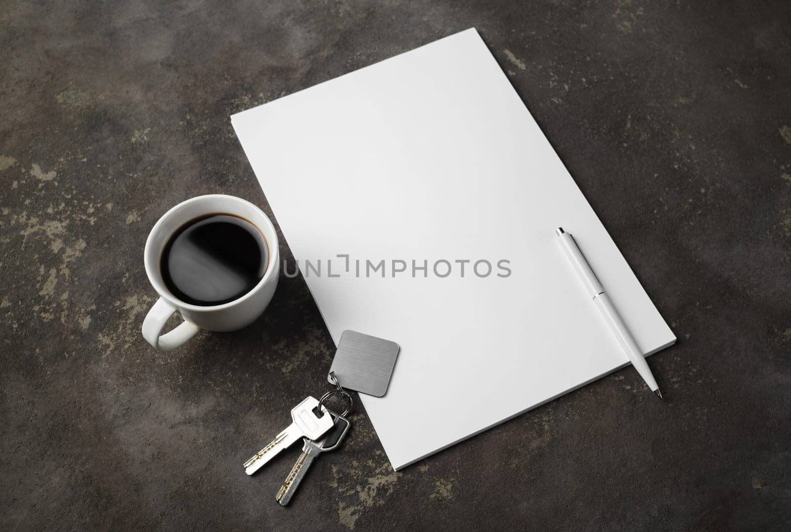 Blank letterhead, key, pen and coffee cup on concrete background. Template for branding identity.