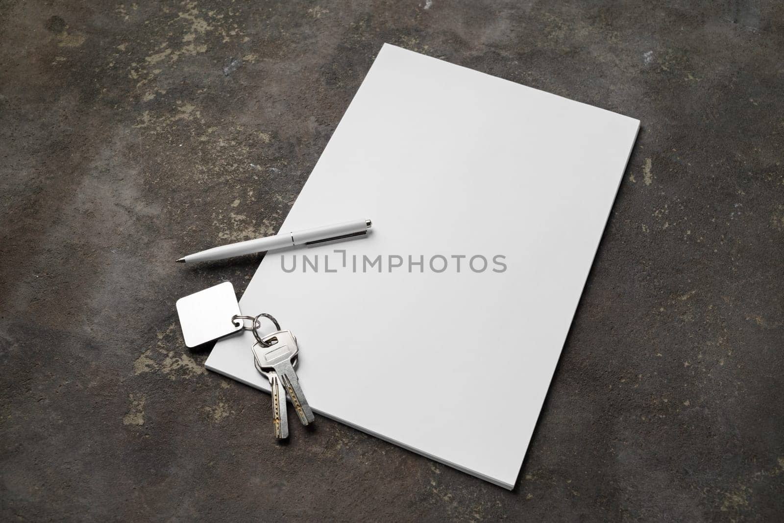 Blank paper, pen and key on concrete background. Responsive design mockup.