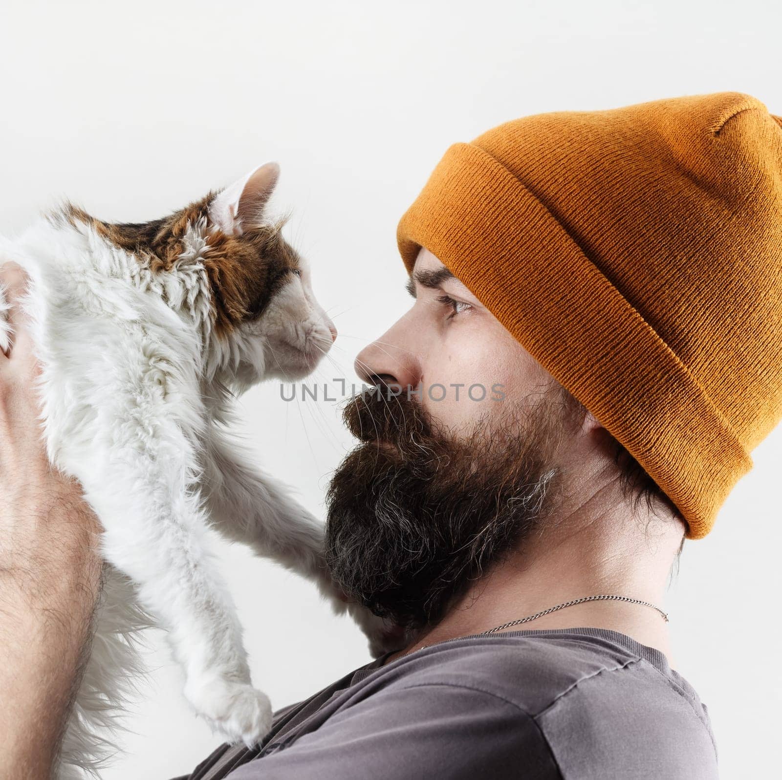 Bearded man in a hat holding a cat. Hipster and his beloved cat.