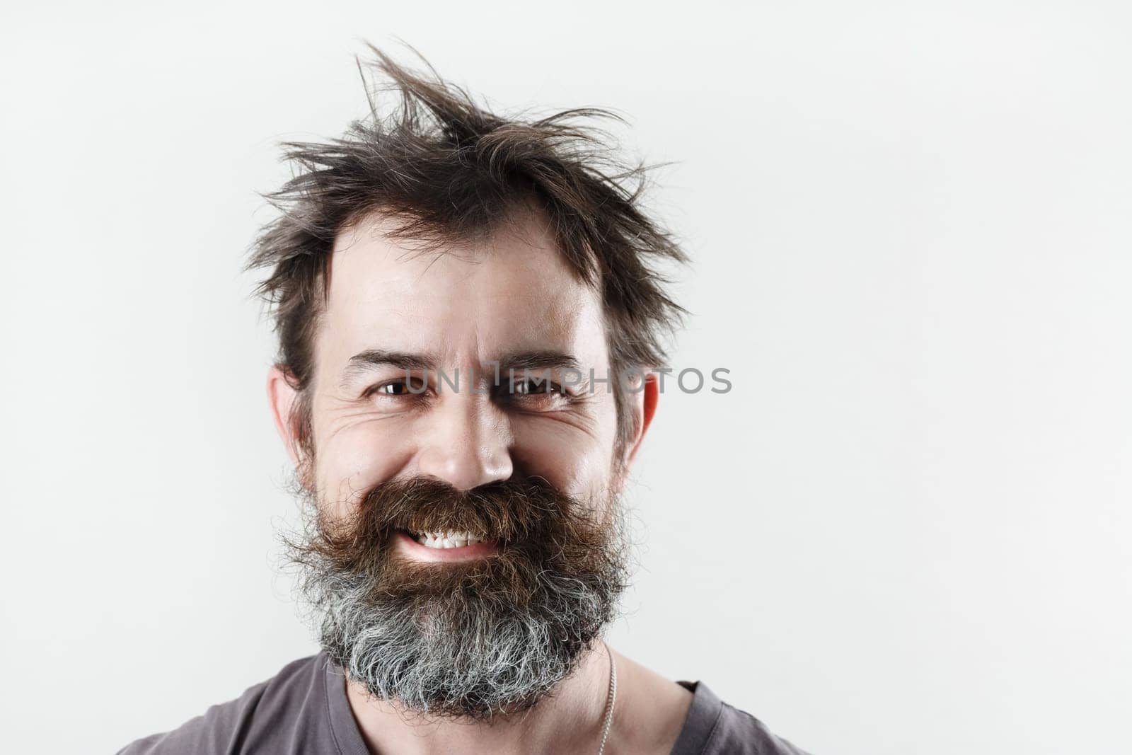 Happy smiling bearded shaggy man. Studio portrait of an unshaven man.