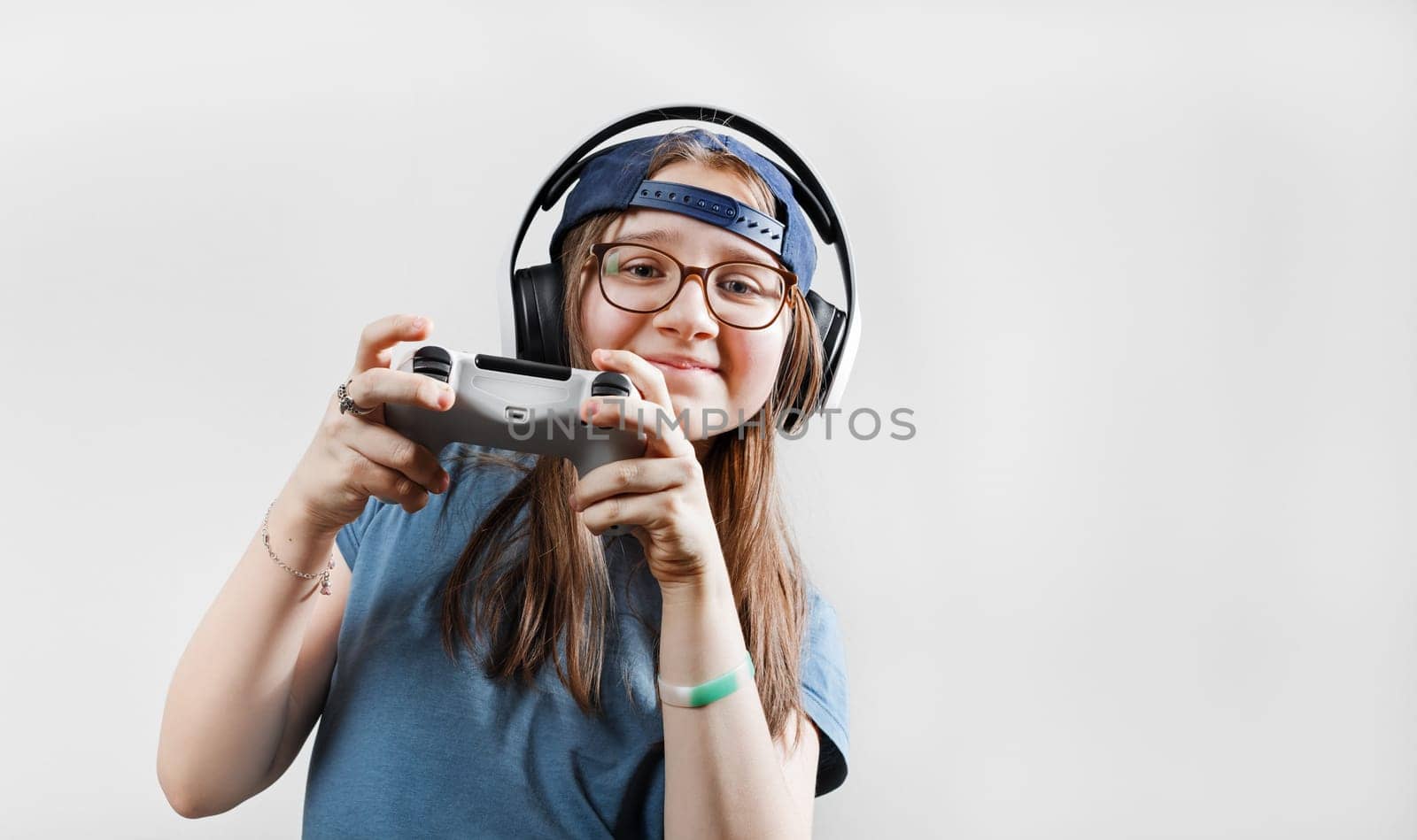 Teen girl in headphones plays video games with a gamepad in her hands. Gamer girl.