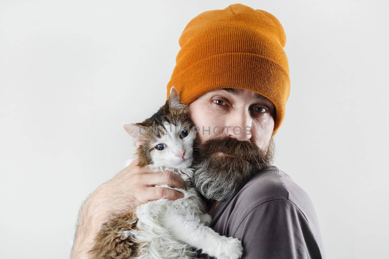 Bearded man hugging a cat. Hipster man in a hat and his beloved cat.