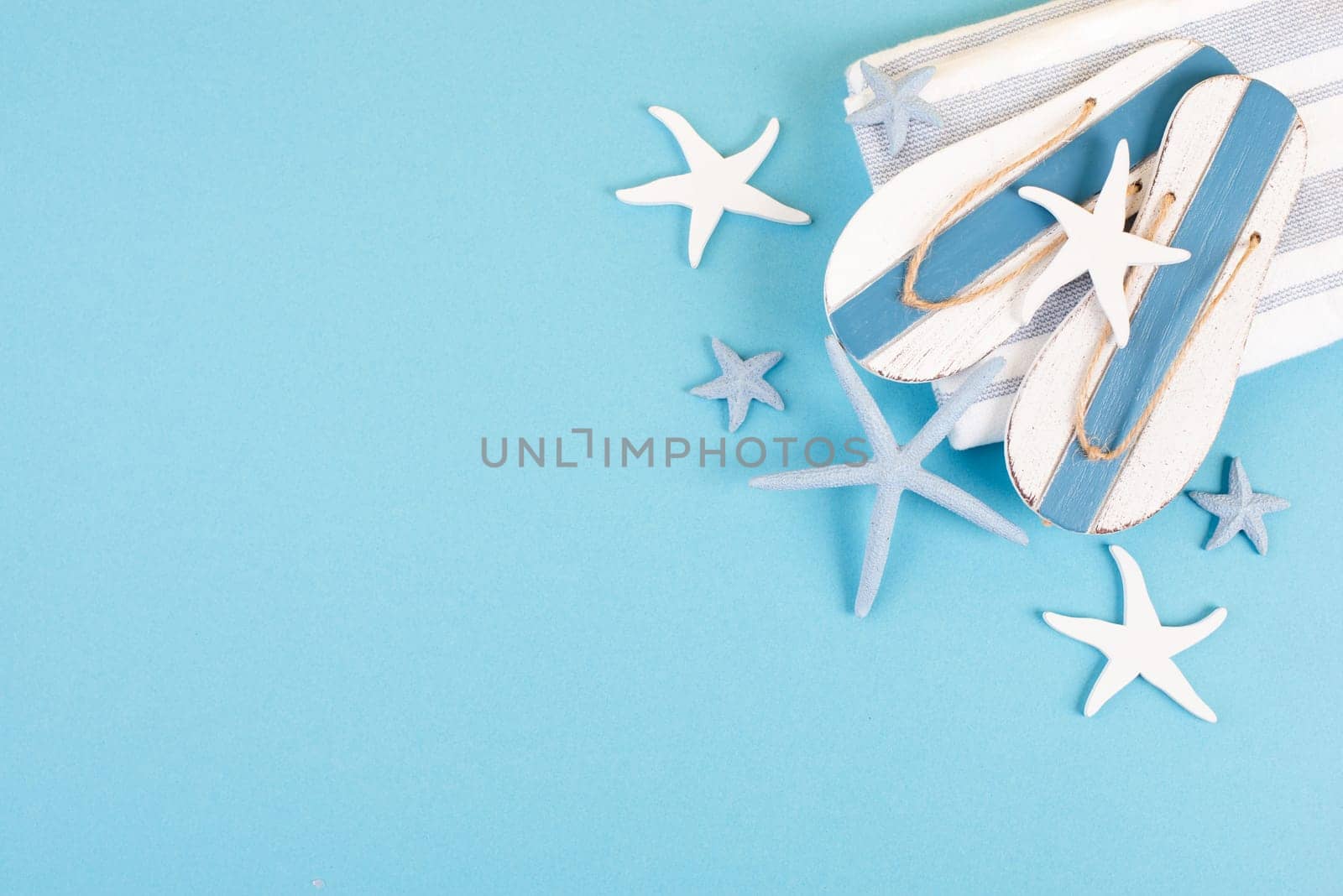 Blue colored summer and vacation background, slippers and sea stars building a frame, copy space for text, holiday and tourism concept