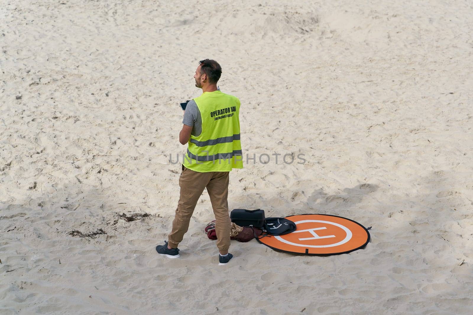User of a drone on the beach of Kolobrzeg on the Baltic Sea in Poland. Translation: UAV operator, keep distance