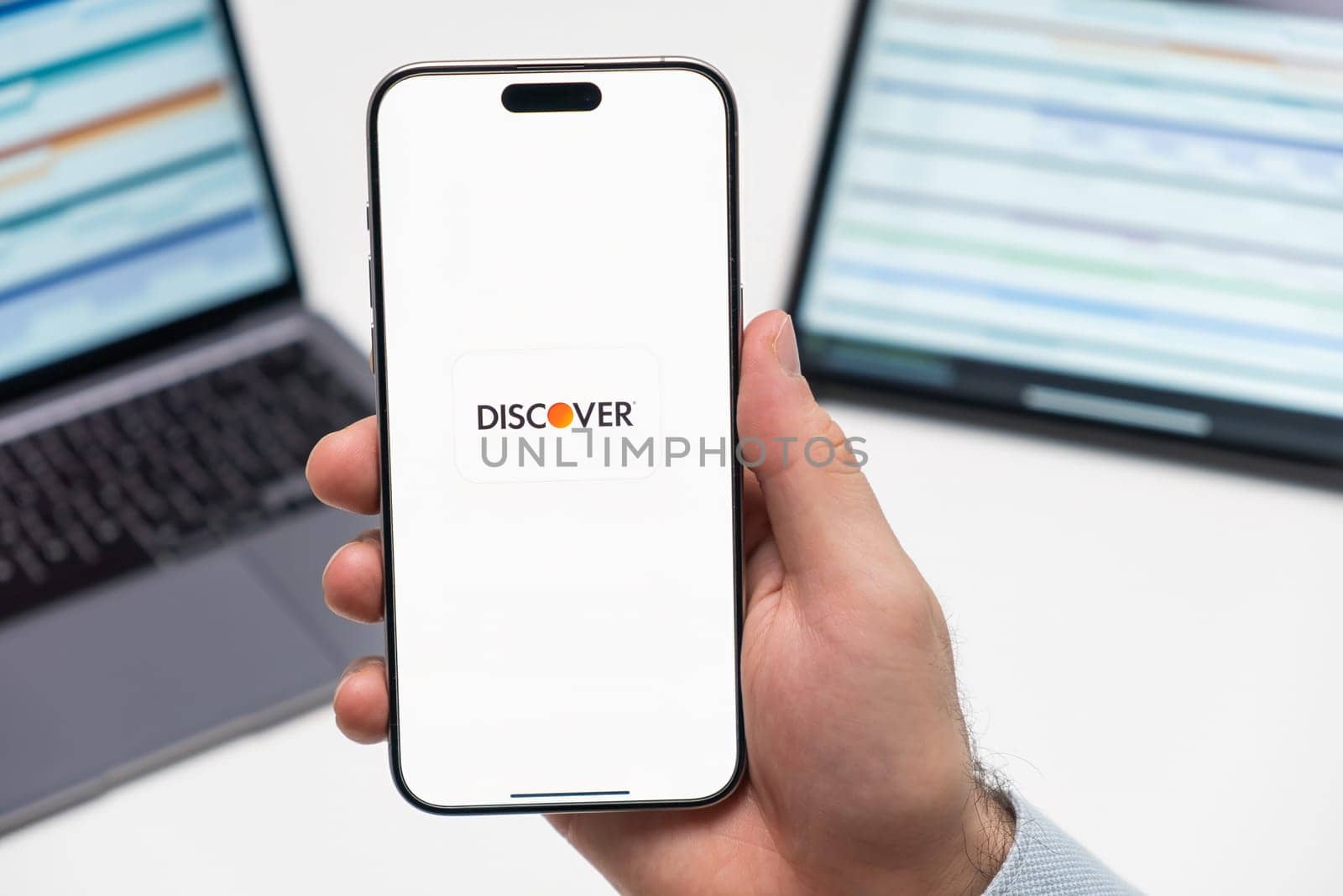 PRAGUE, CZECH REPUBLIC - JANUARY 21 2024: Discover logo on the screen of smartphone in mans hand on the workplace background.