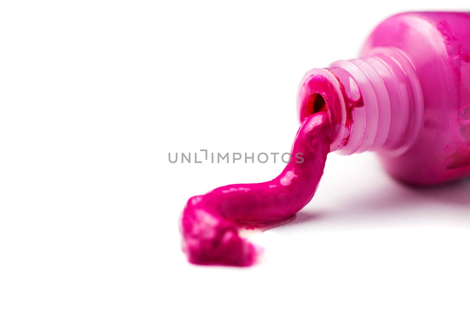 Close-up of an open tube of magenta artist paint spilling out on a white background.