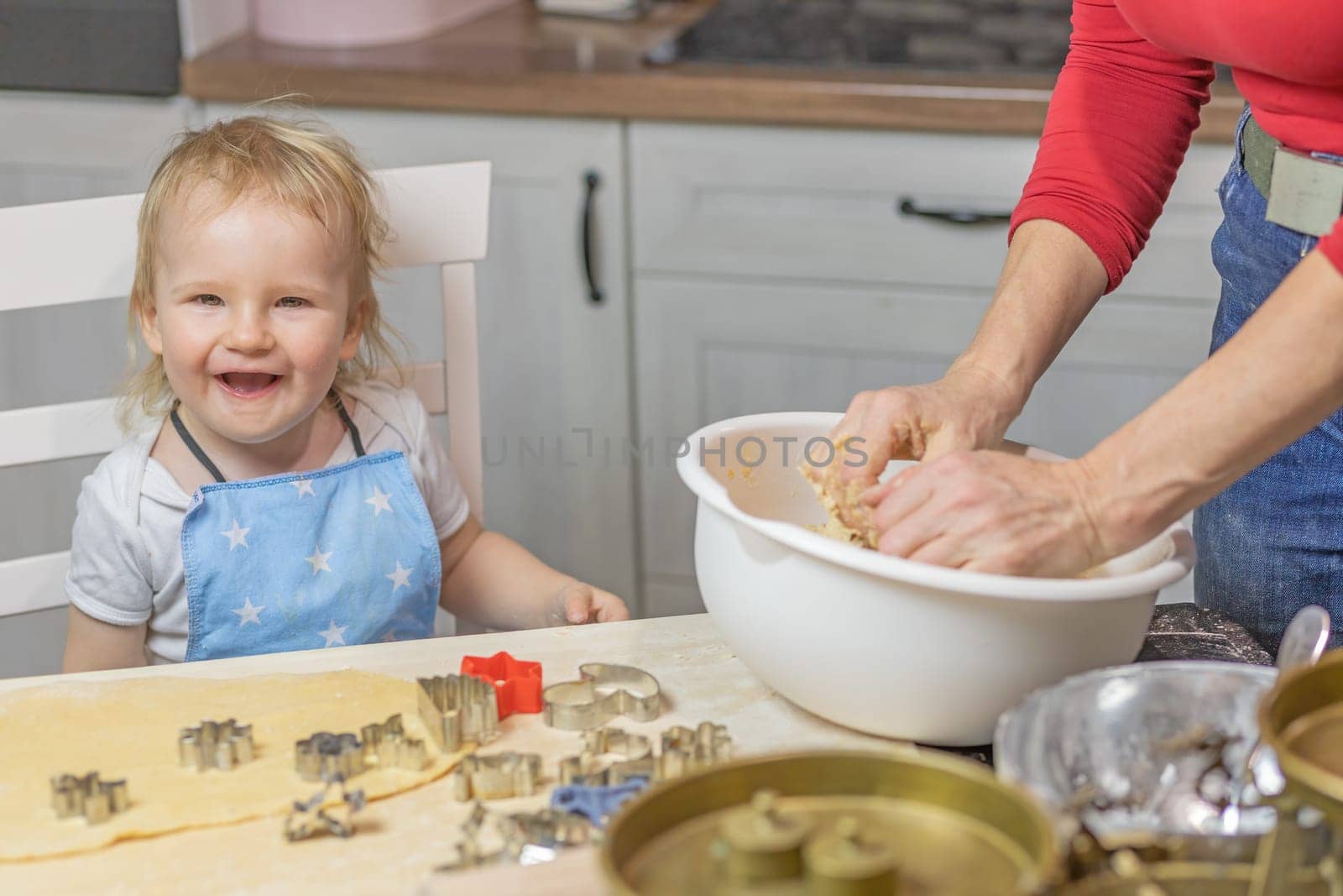 Smiling little child boy is baking cake in domestic kitchen. Horizontally.