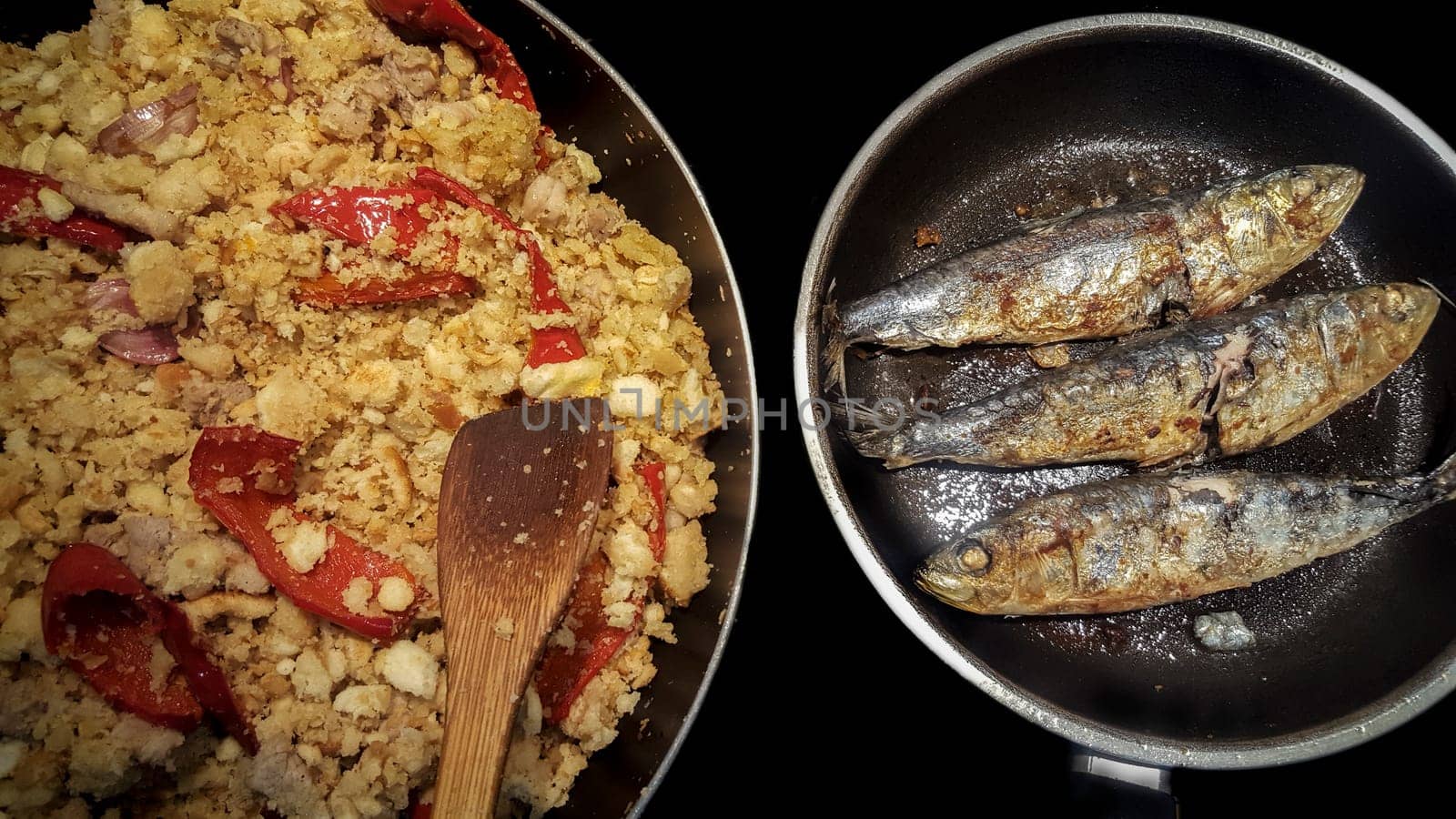 Sapnish migas with roasted sardines cooked in two pans. High view angle