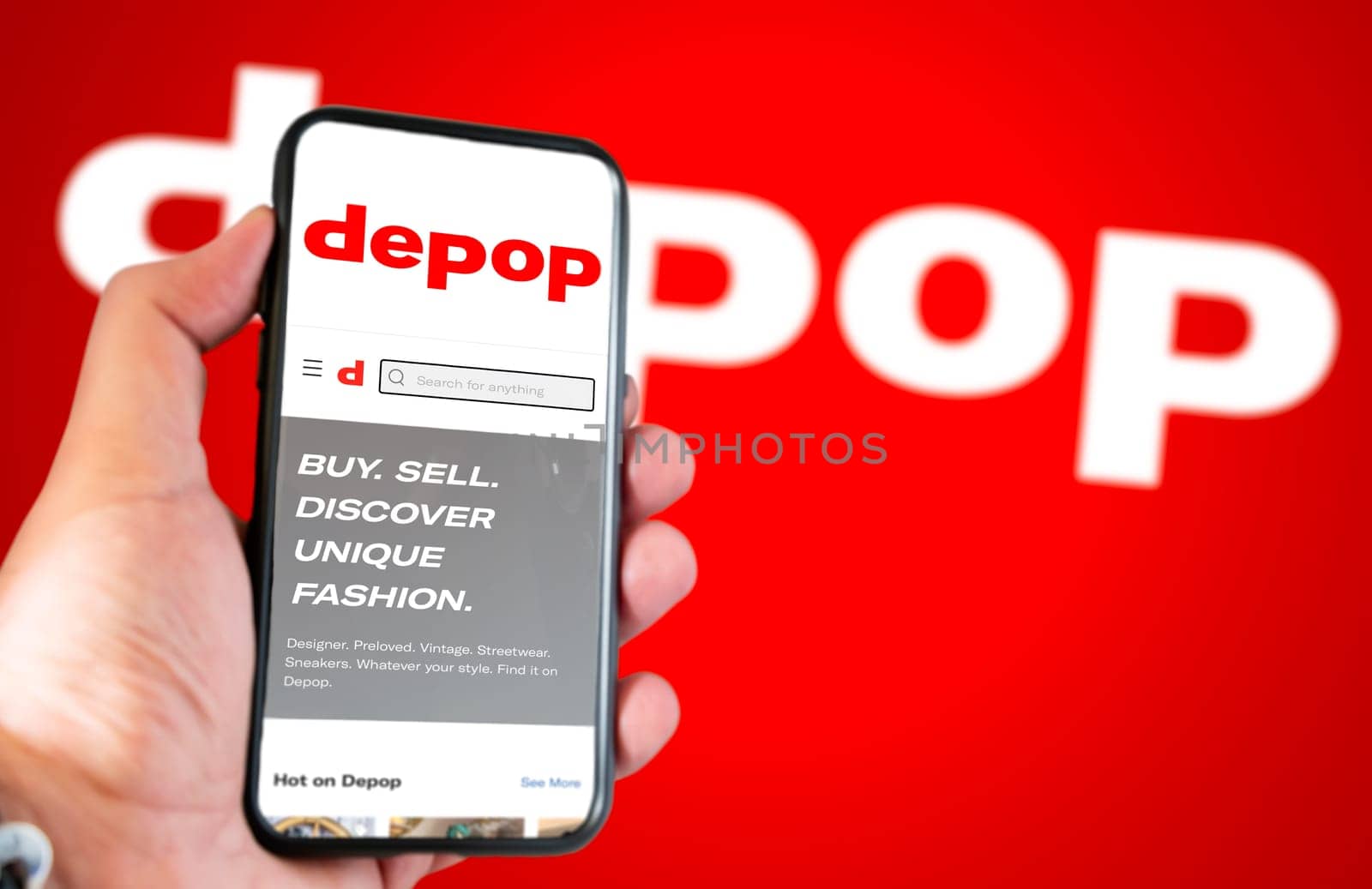 Roncade, Italy, May 2022: Depop company’s website on a phone screen. Red background with Depop logo blurred. Illustrative editorial. Selective focus. Depop is a peer-to-peer social e-commerce company