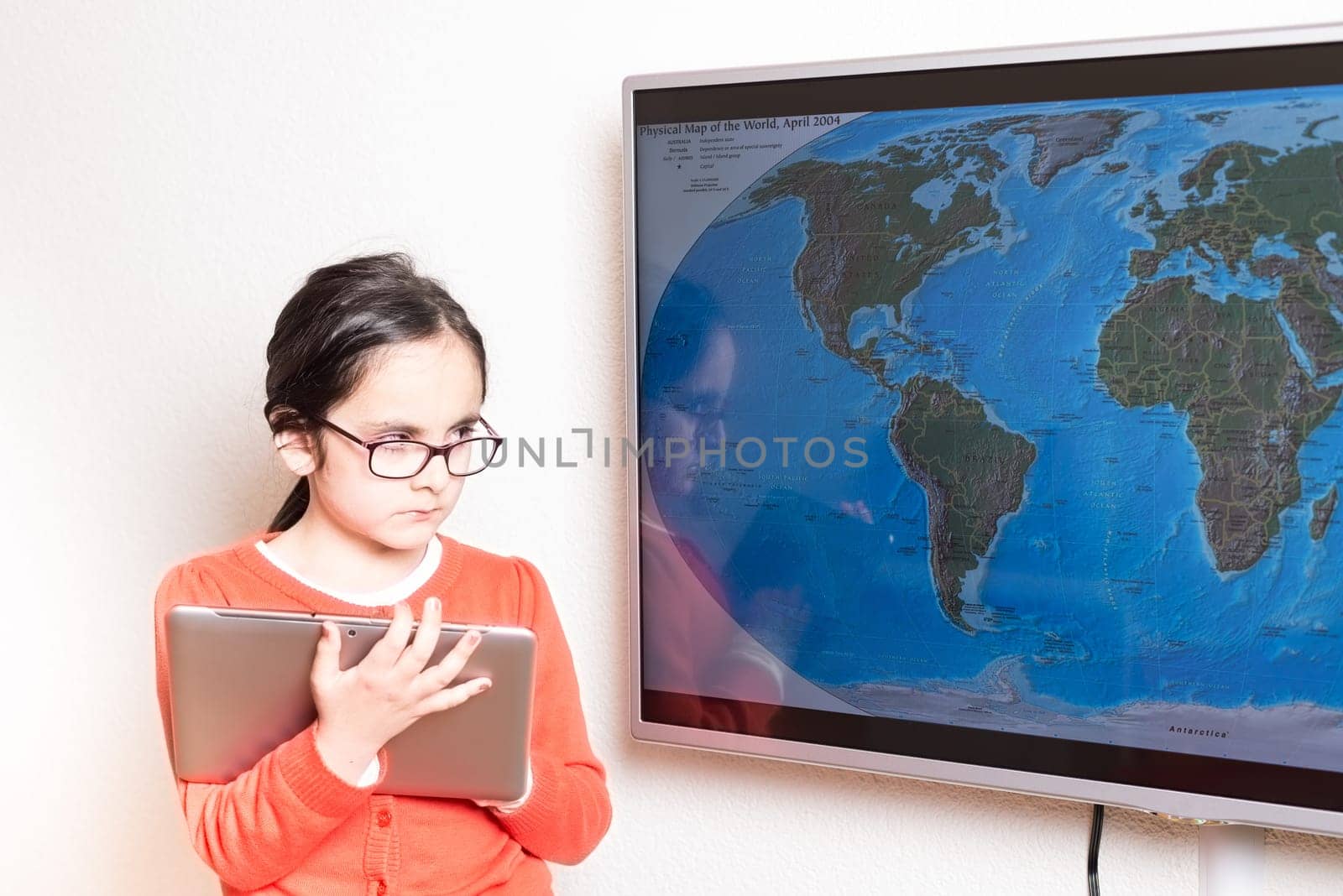 Little cute girl using at home a Tablet PC and an interactive television for homework