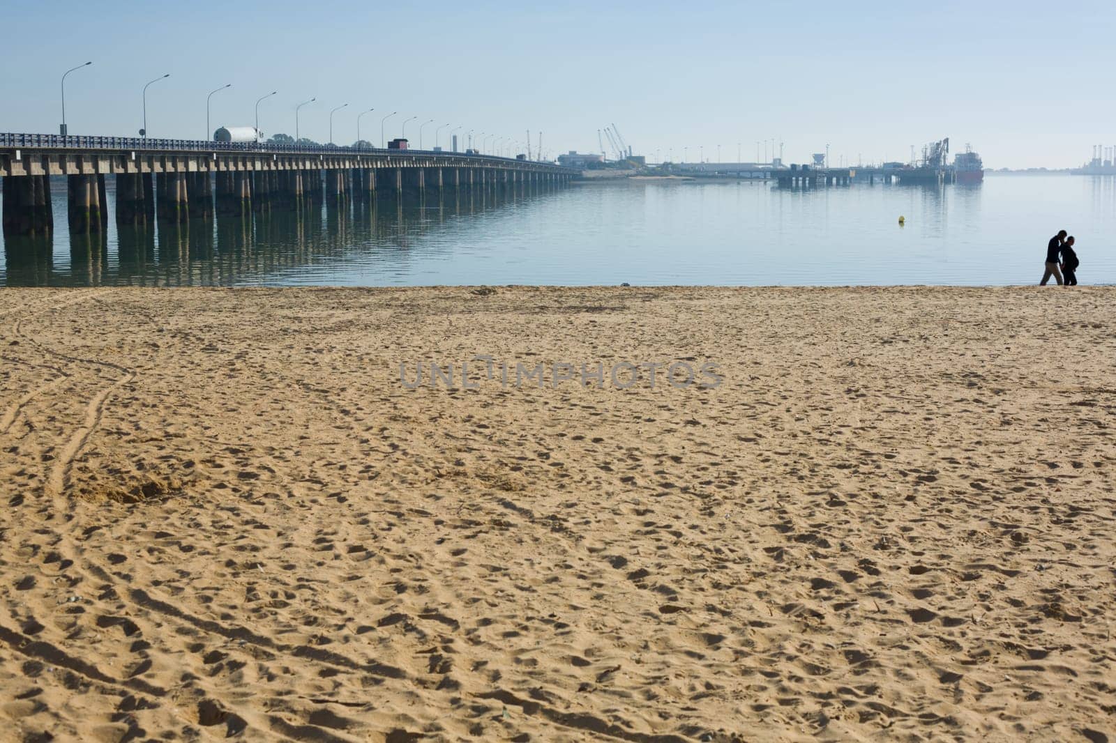 Wooden beach with couple in love at bottom, she is pregnant and he is phoning