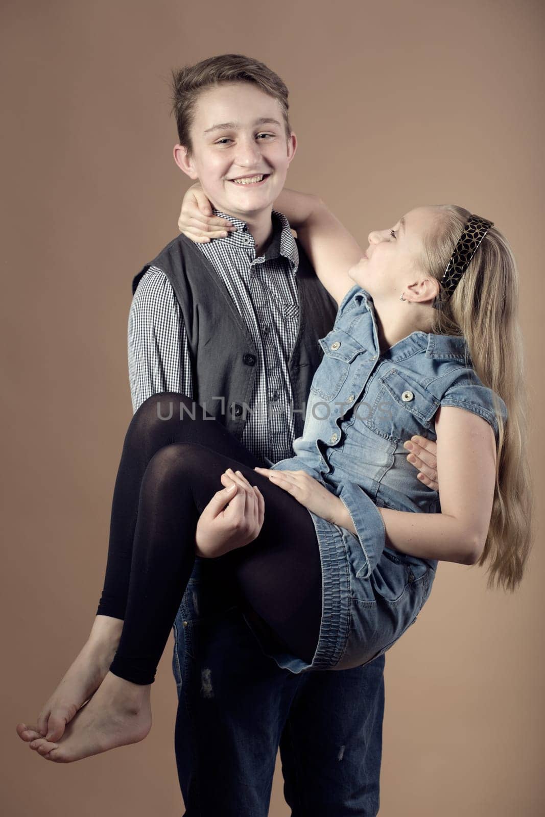 fashion smiling european little long hair blonde girl and her brother posing in atelier