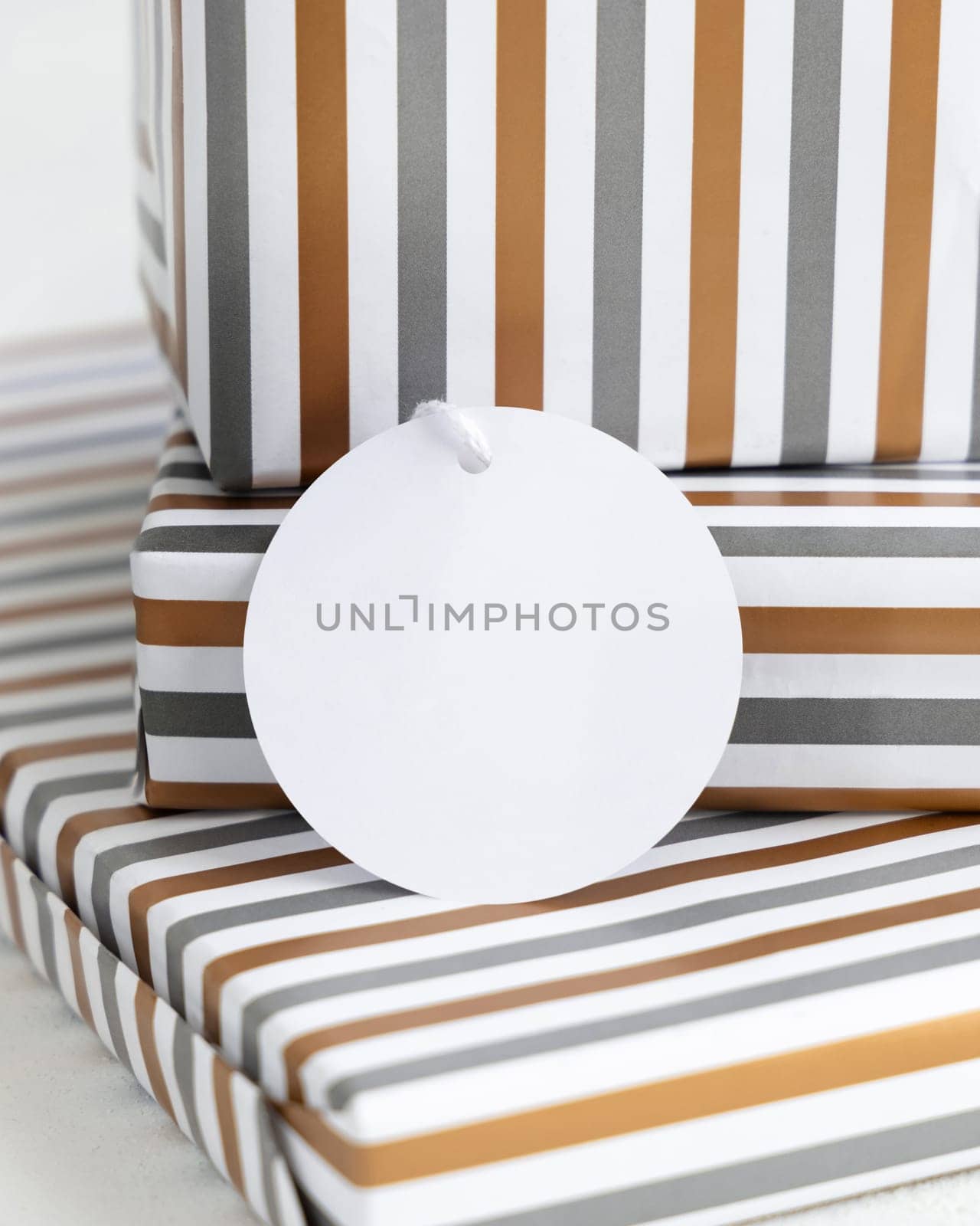 Presents with blank round gift tag close up. Gift boxes wrapped in Striped geometric paper. Christmas, New Year, Birthday, Anniversary label mockup