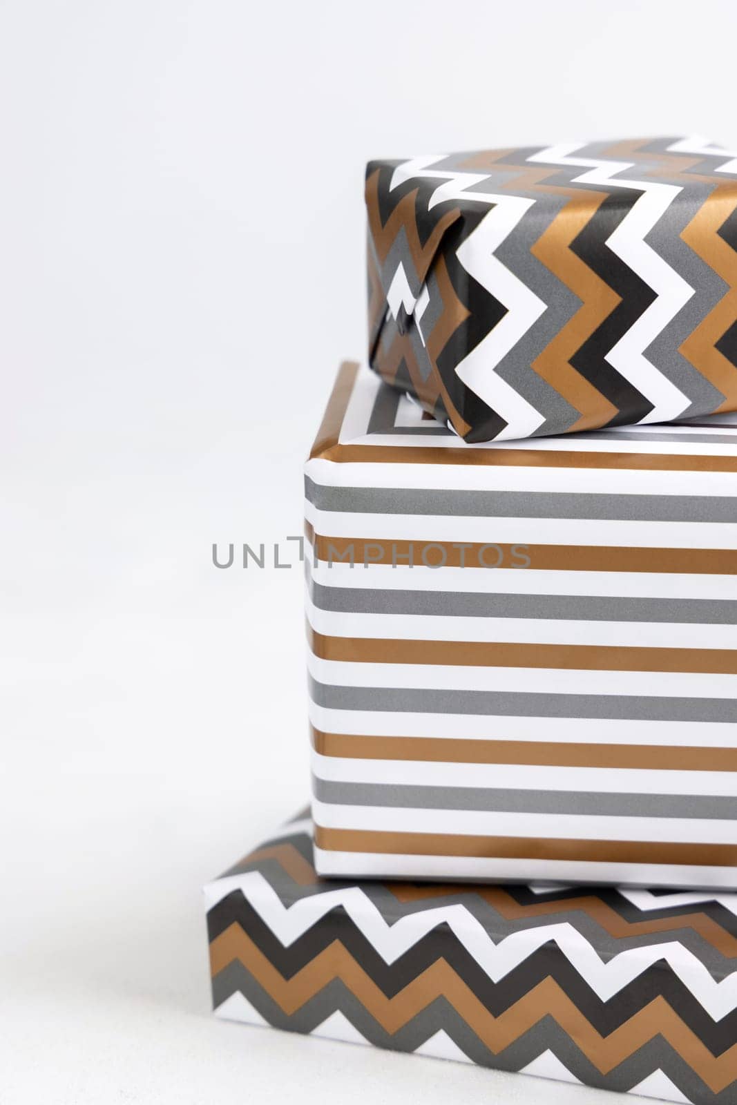 Presents Wrapped in striped and chevron geometric paper on white table close up. Christmas, New Year, Birthday, Anniversary concept