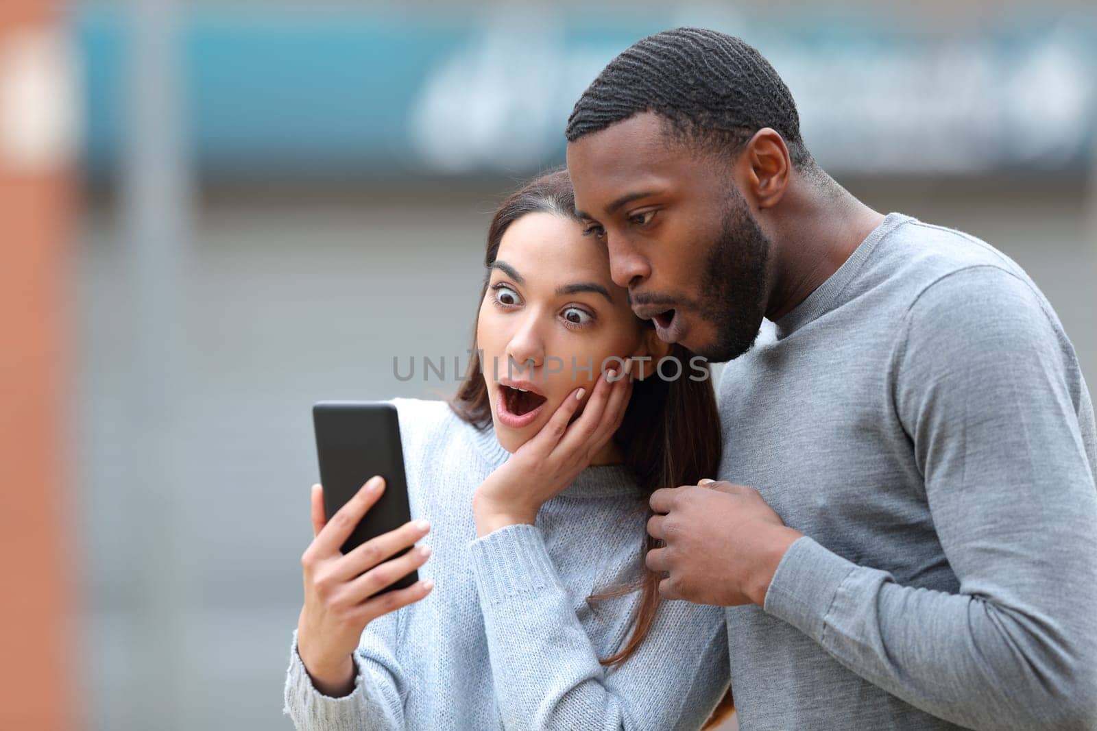 Amazed interracial couple checking phone news