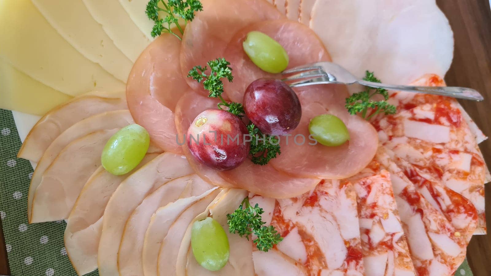 Food tray with delicious salami, pieces of ham, sausage, tomatoes, lettuce and vegetables - meat platter with selection - cut sausage and sausage on a celebratory table.