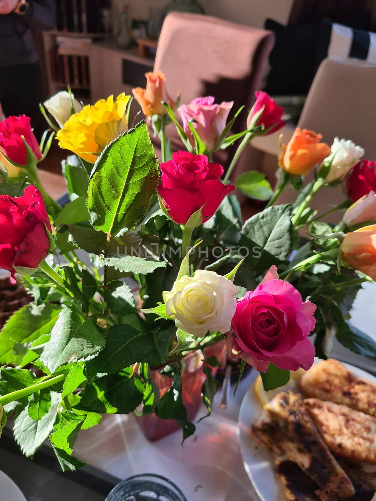 A bouquet of roses in a vase on a bedside table