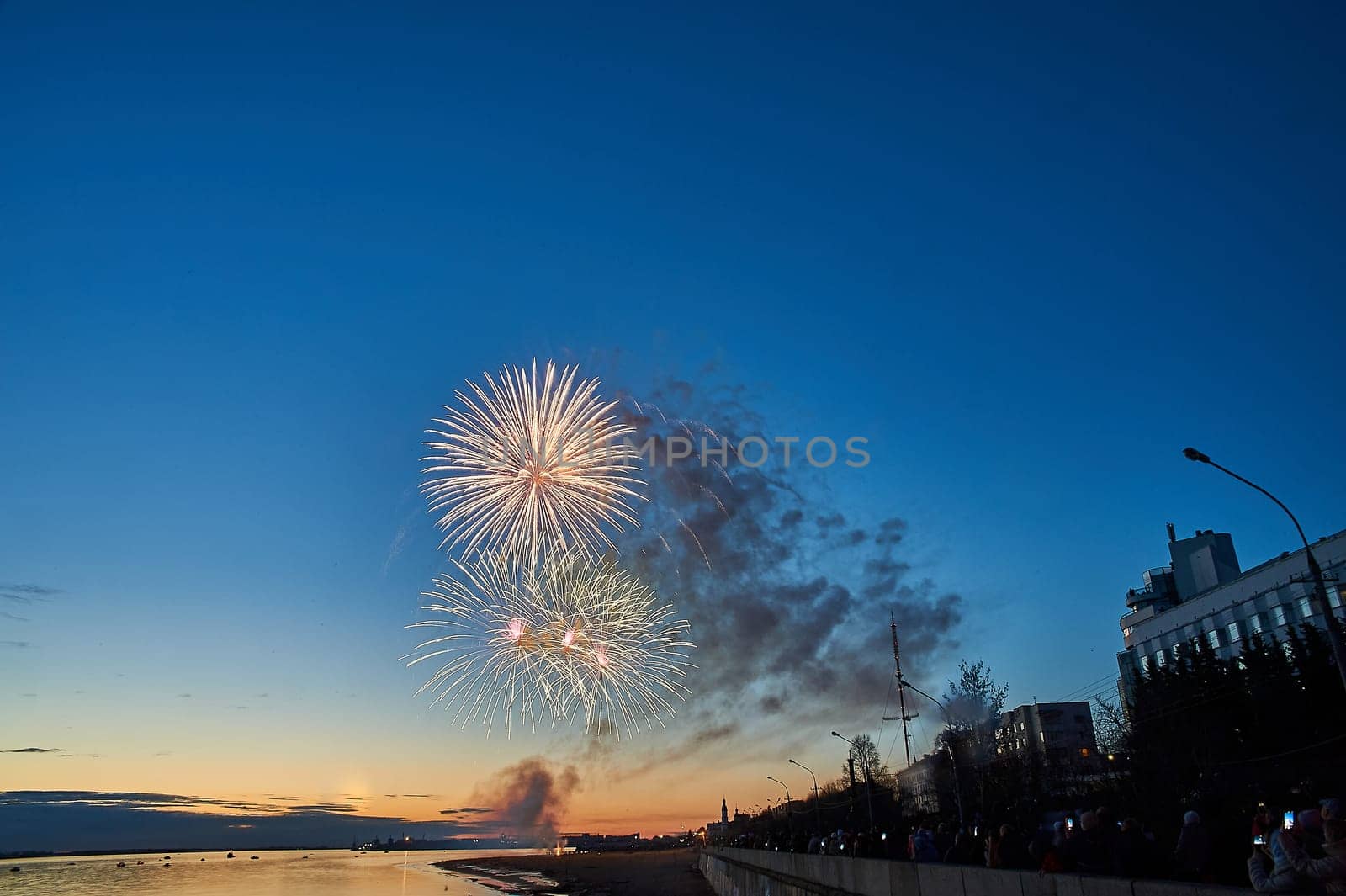 Colorful fireworks on the background of the sky on the river bank. High quality photo