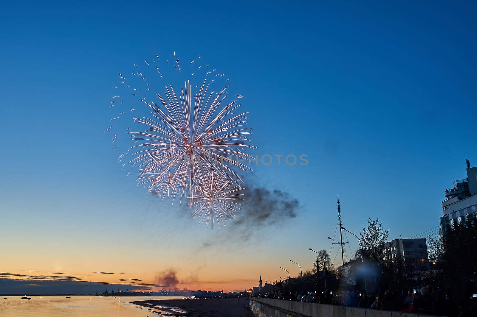 Colorful fireworks on the background of the sky on the river bank. High quality photo