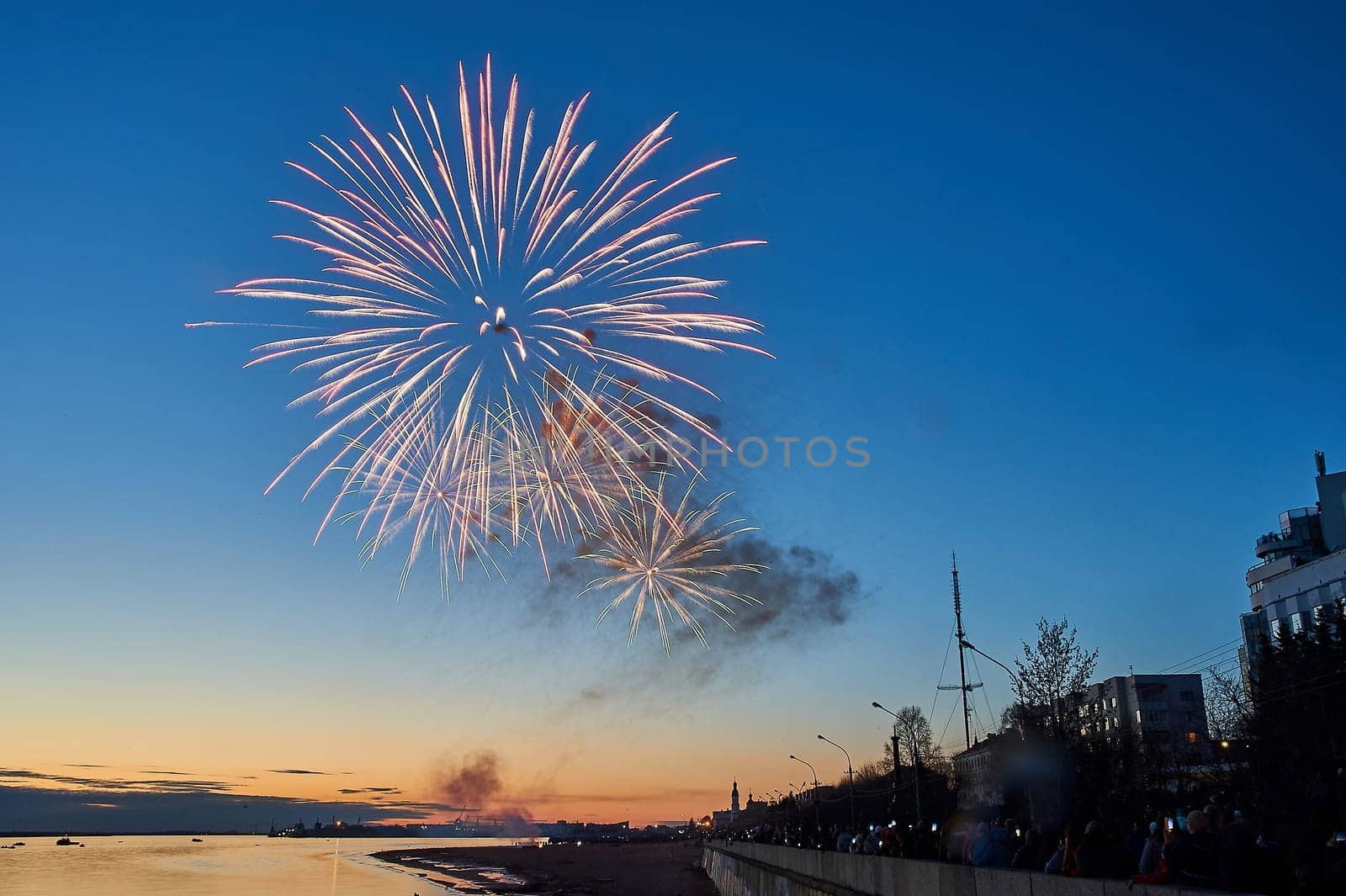 Colorful fireworks on the background of the sky on the river bank. High quality photo
