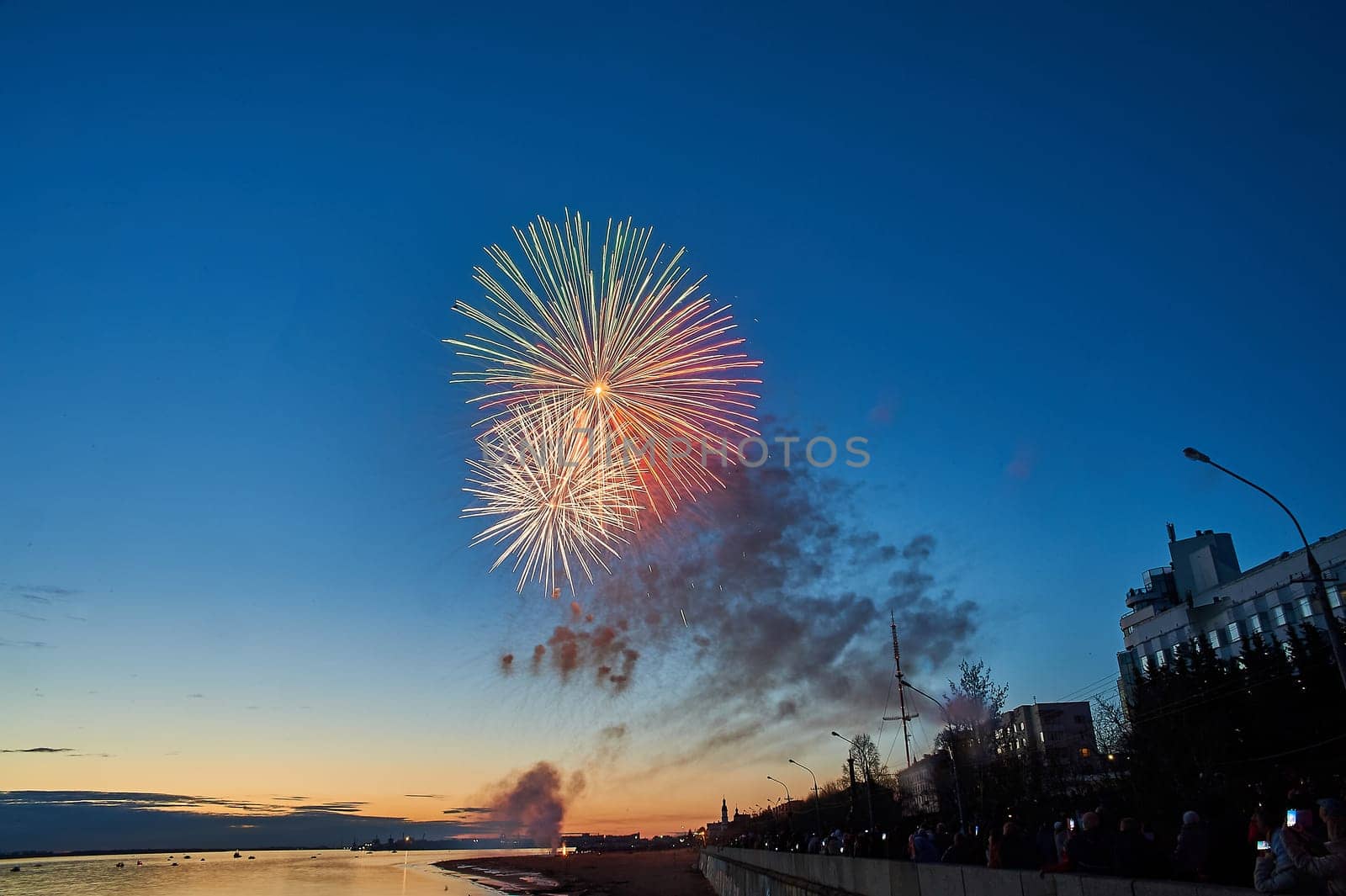 Colorful fireworks on the background of the sky on the river bank. High quality photo
