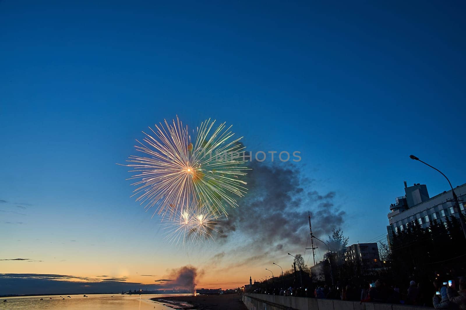 Colorful fireworks on the background of the sky on the river bank. High quality photo