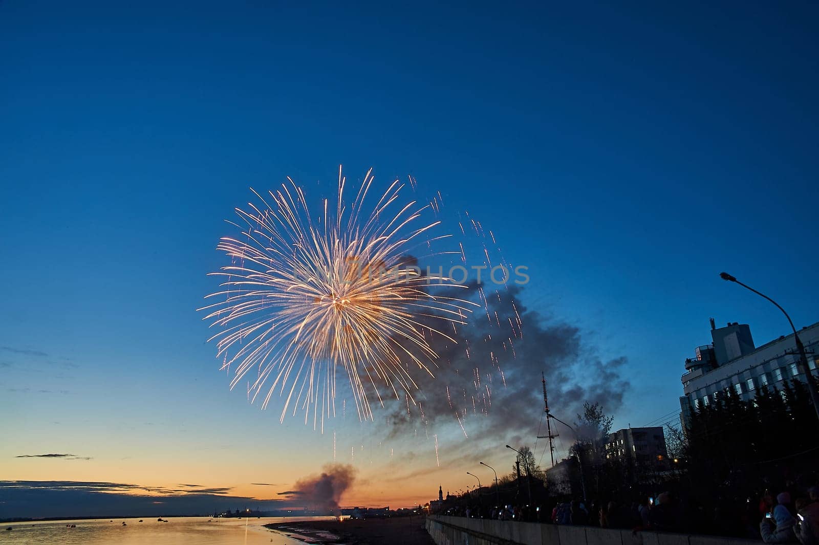 Colorful fireworks on the background of the sky on the river bank. High quality photo