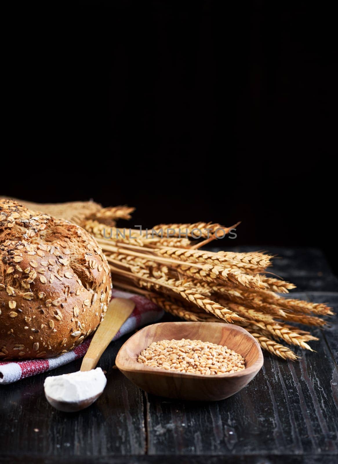 Bread and wheat ears on dark wooden board with copyspace