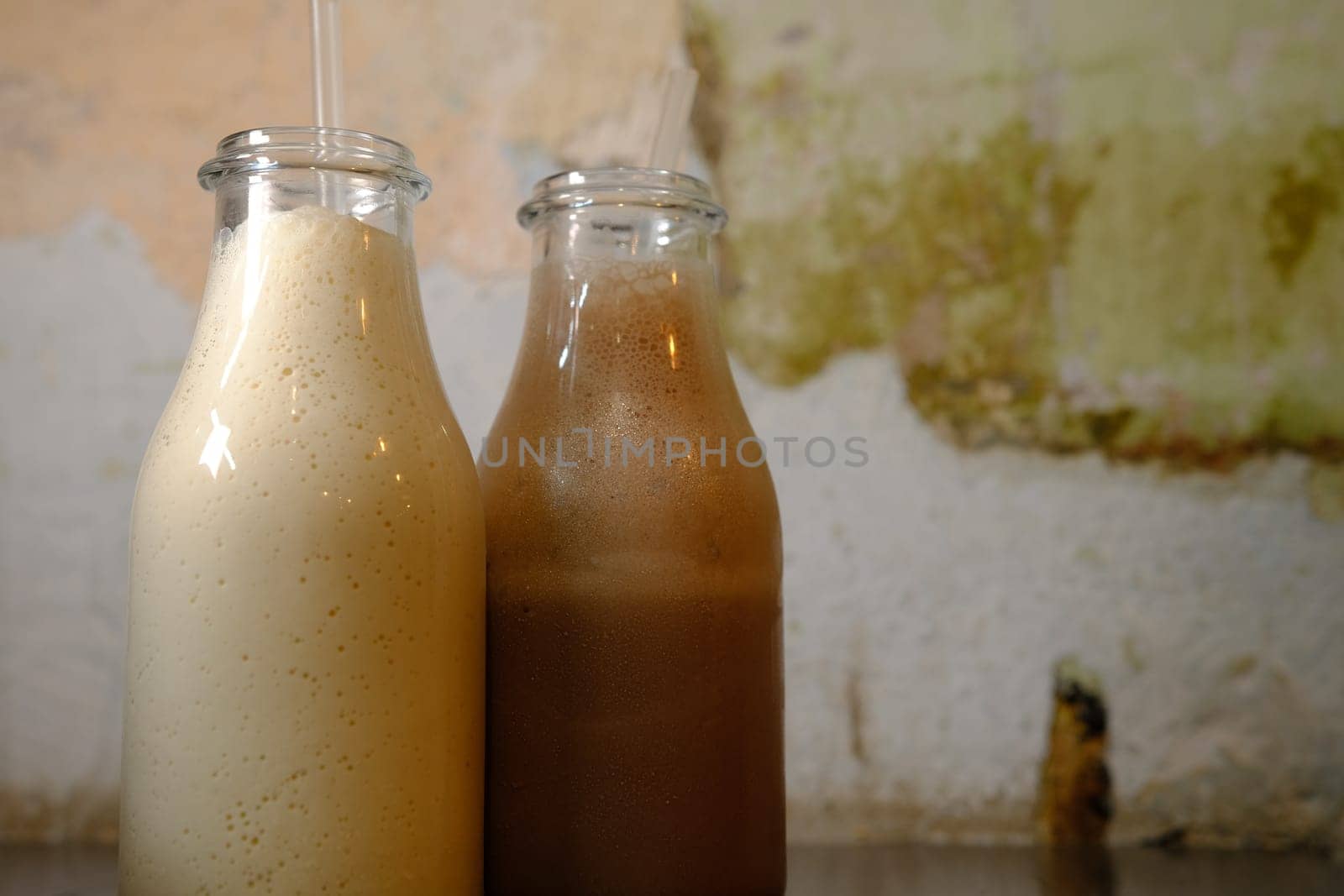 Milkshake chocolate milk in bottles with straws vintage background closu up side view.