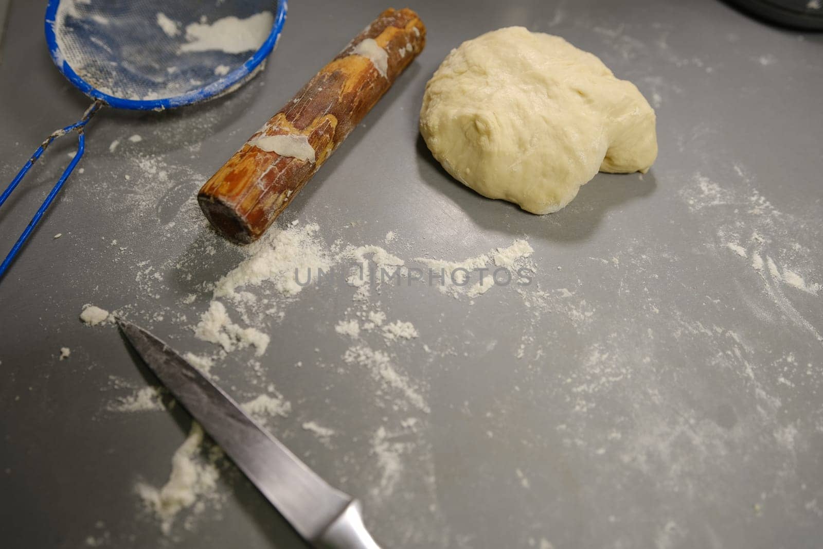 pizza dough with flour rolling pin and knife