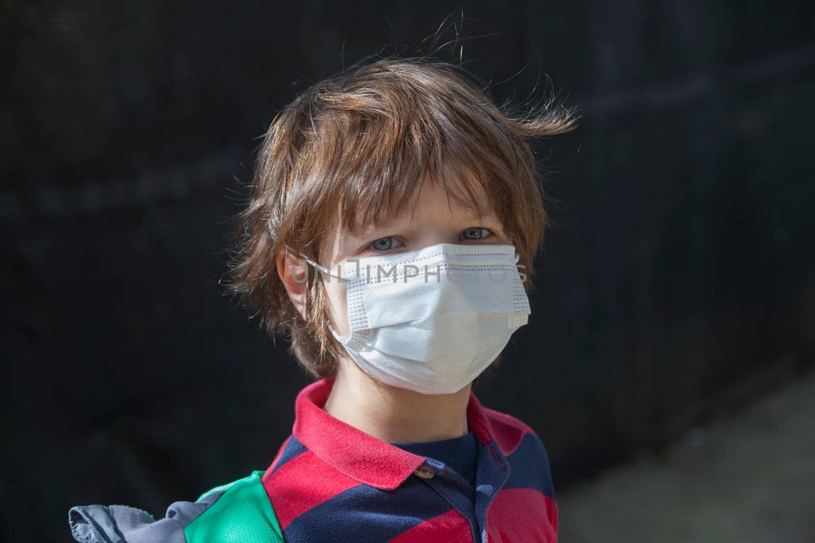 6 years little boy wearing a face mask straight into the camera. He has a stiff gesture