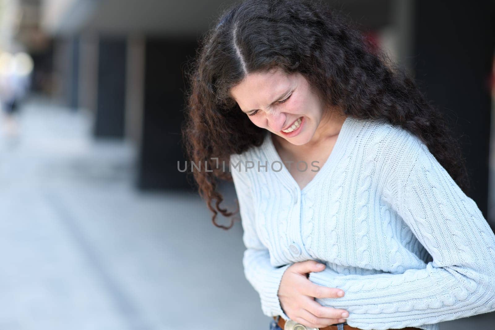 Stressed woman complaining in the street suffering belly ache