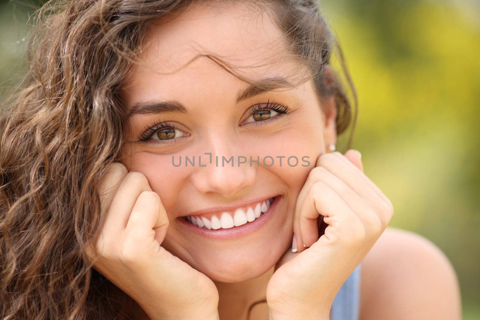 Front view portrait of a beautiful woman with perfect white smile looking at camera in a park