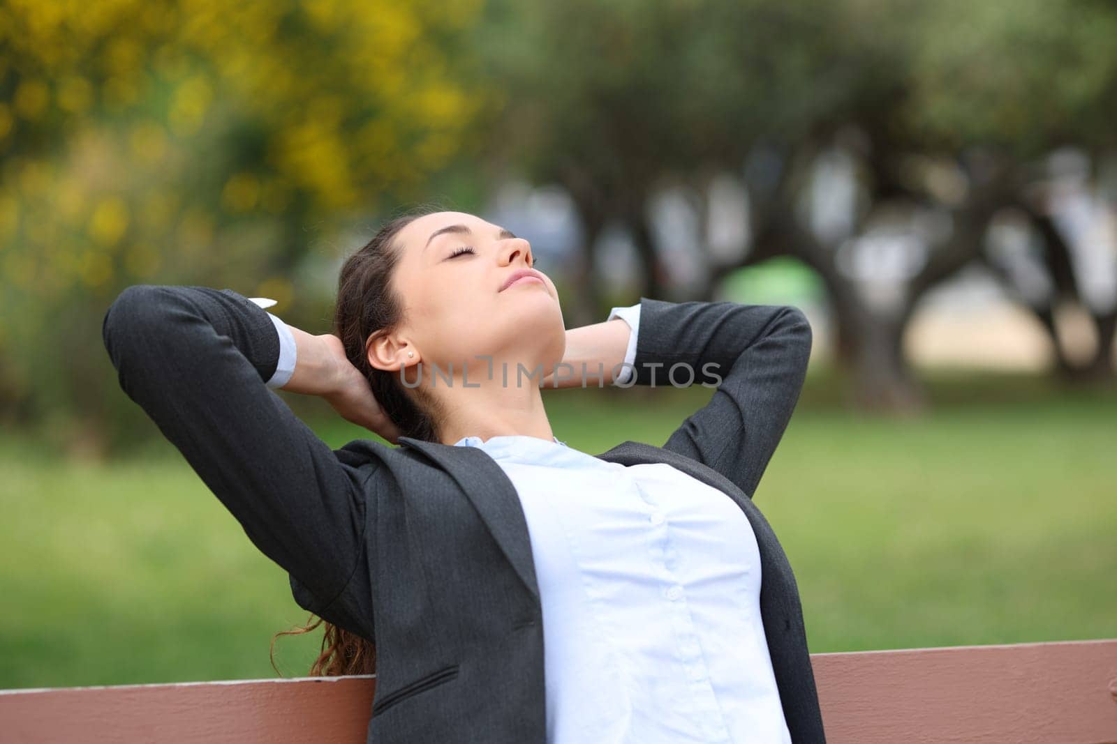 Businesswoman relaxing resting sitting on a bench in a park