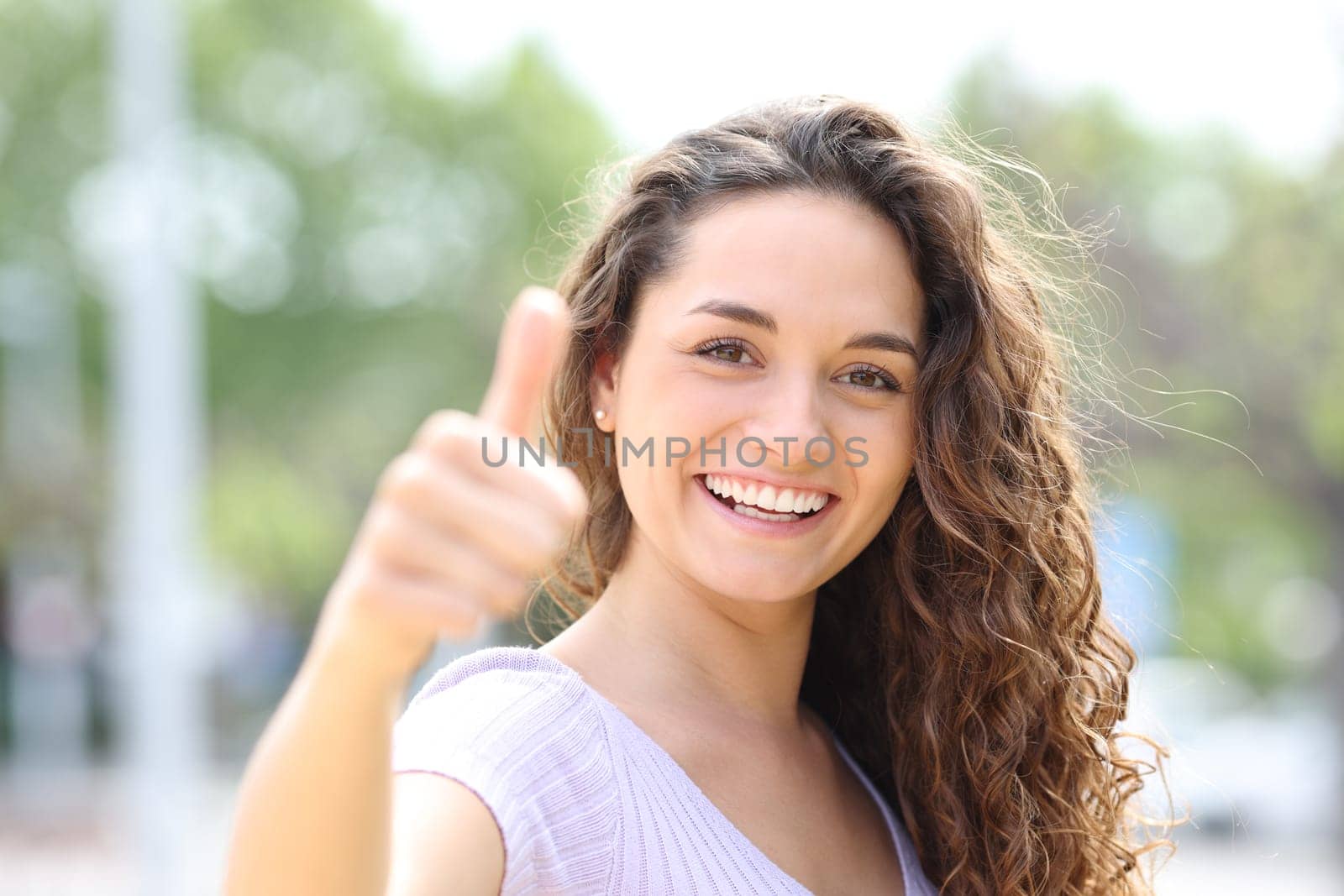 Front vie wportrait of a happy woman gesturing thumbs up smiling in a park