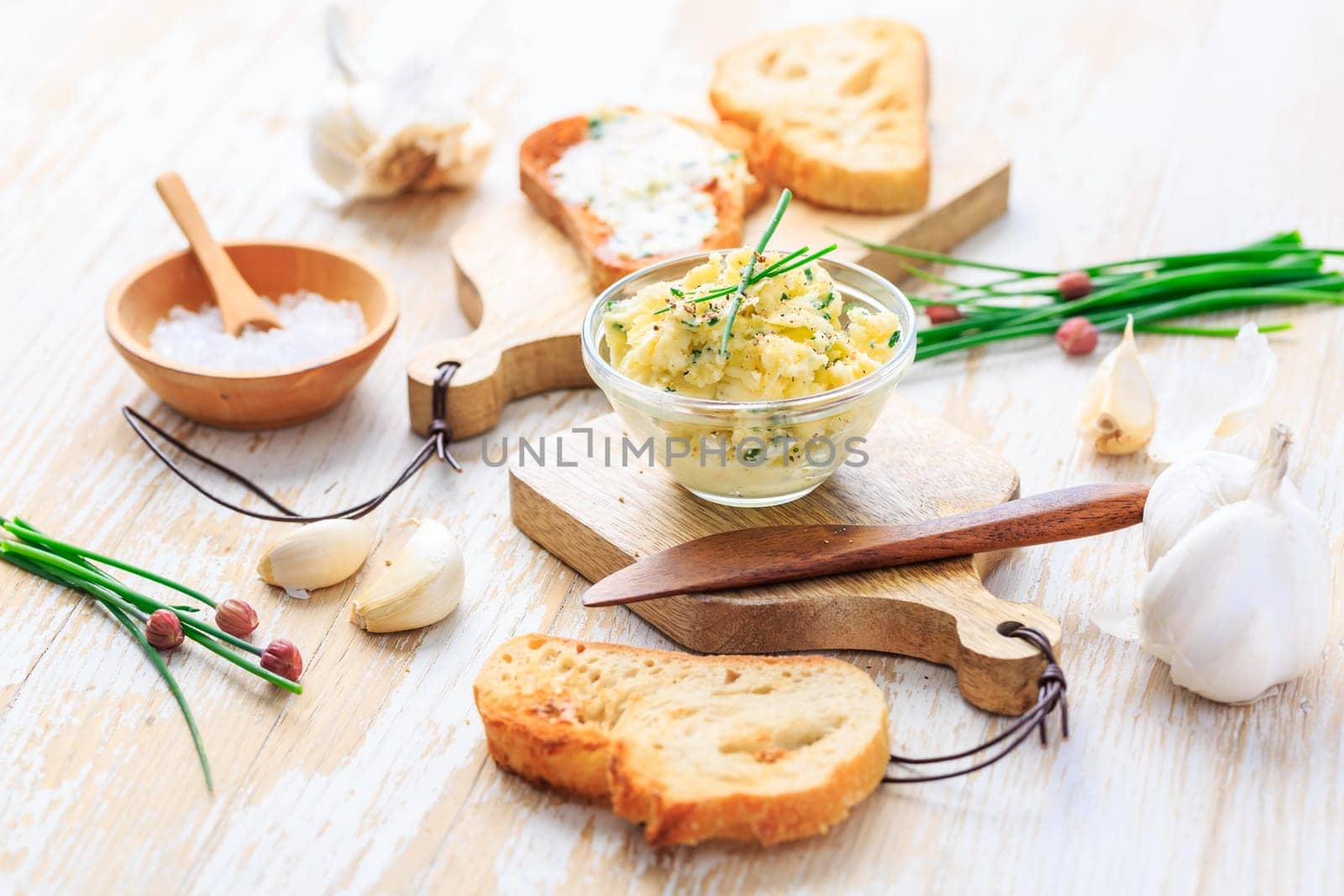 Homemade garlic butter with herbs and chives and fresh roasted baguette with salt