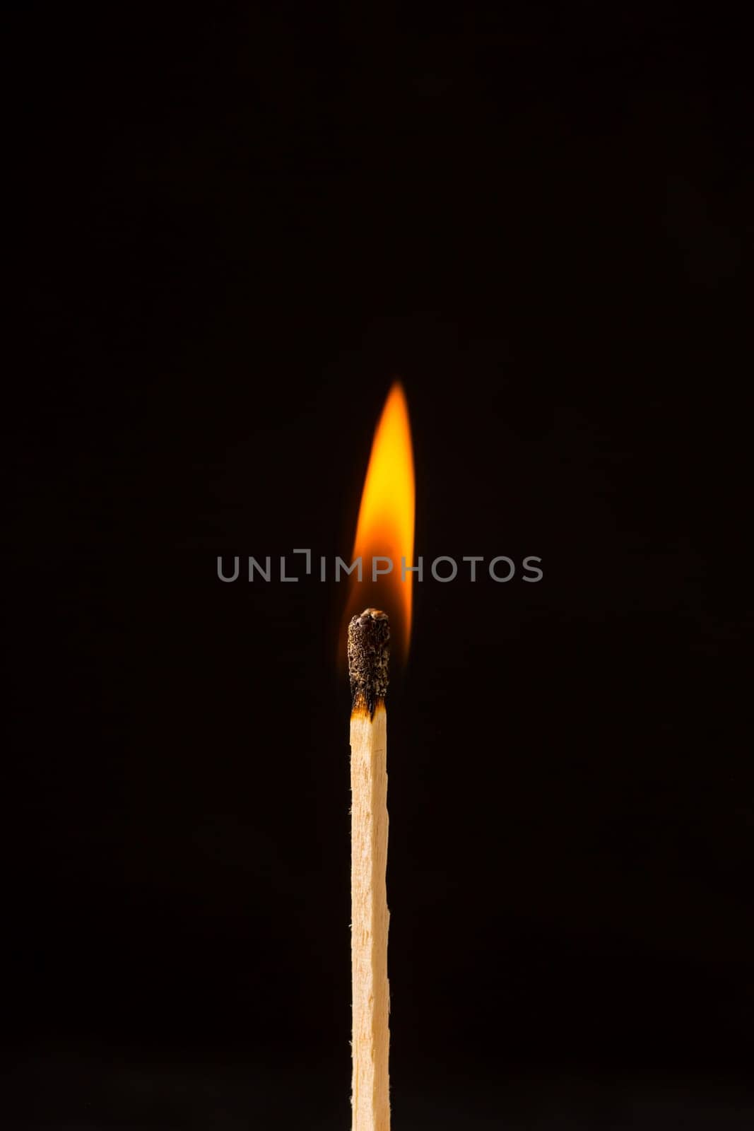 Burning matchstick on black background