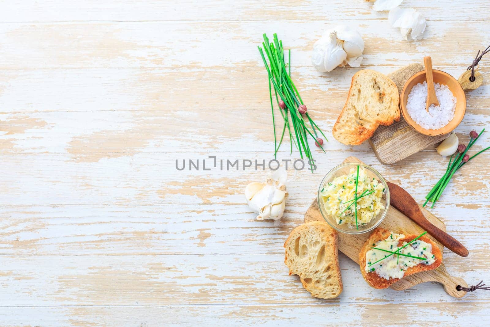 Homemade garlic butter with herbs and chives and fresh roasted baguette with salt and copy space