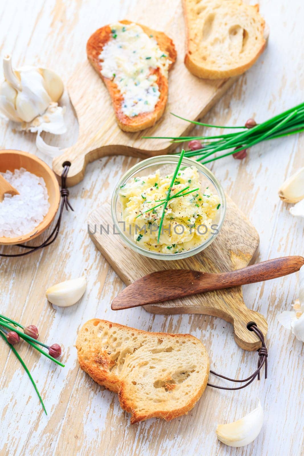 Homemade garlic butter with herbs and chives and fresh roasted baguette with salt
