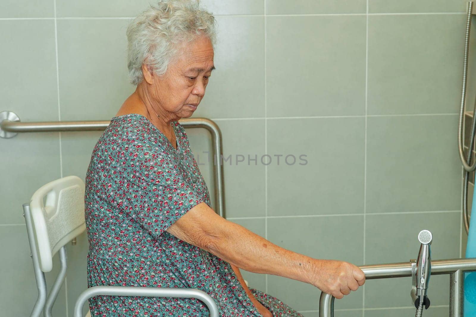 Asian elderly old woman patient use toilet support rail in bathroom, handrail safety grab bar, security in nursing hospital.