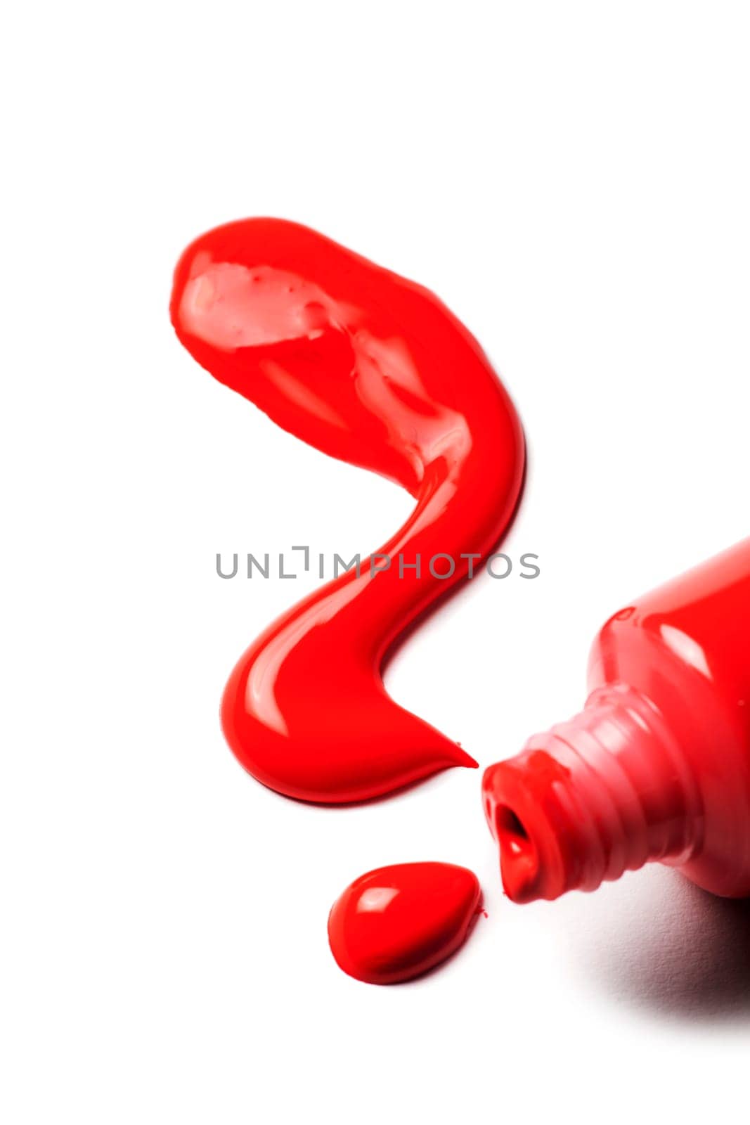 Close-up of an open tube of artist paint with red acrylic paint spilling out in the shape of a question mark on a white background.