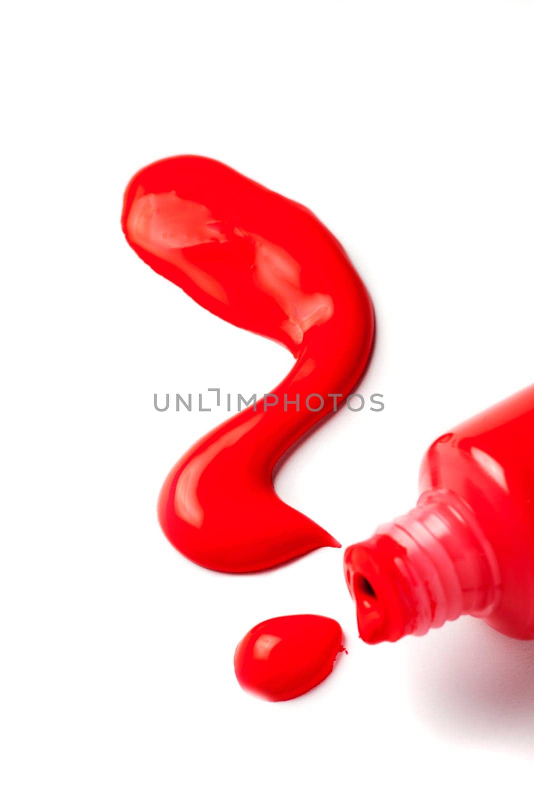 Close-up of an open tube of artist paint with red acrylic paint spilling out in the shape of a question mark on a white background.