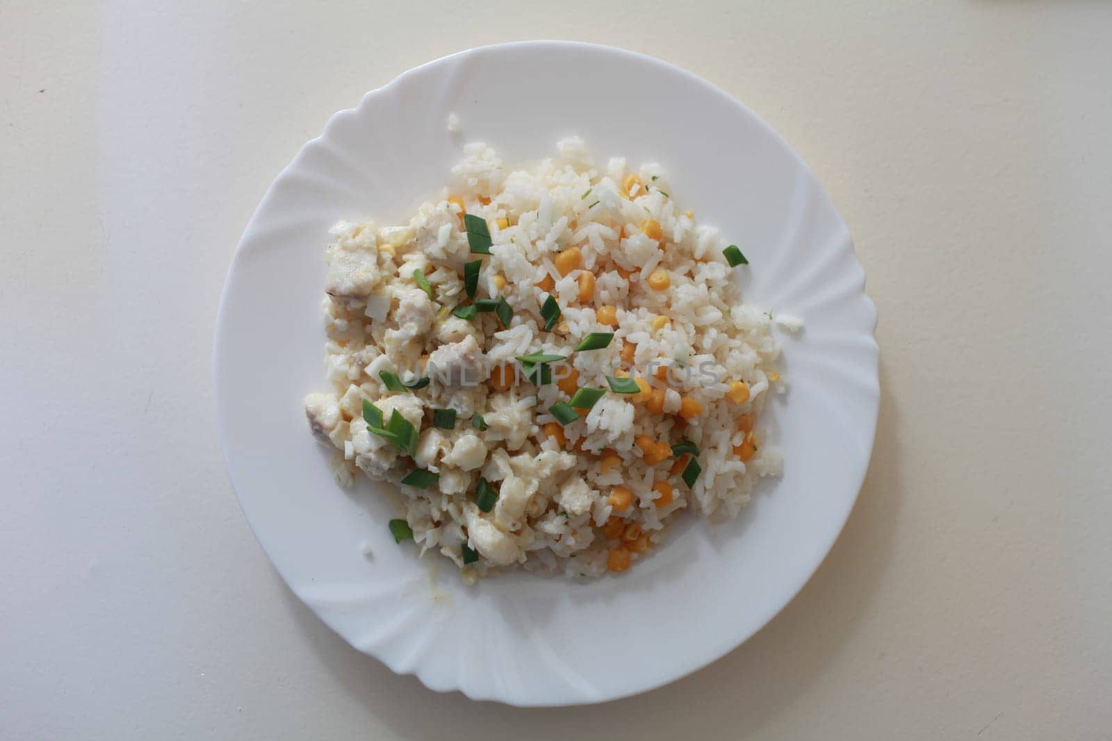 dish with rice, green onions, corn and fish on a plate overhead shot