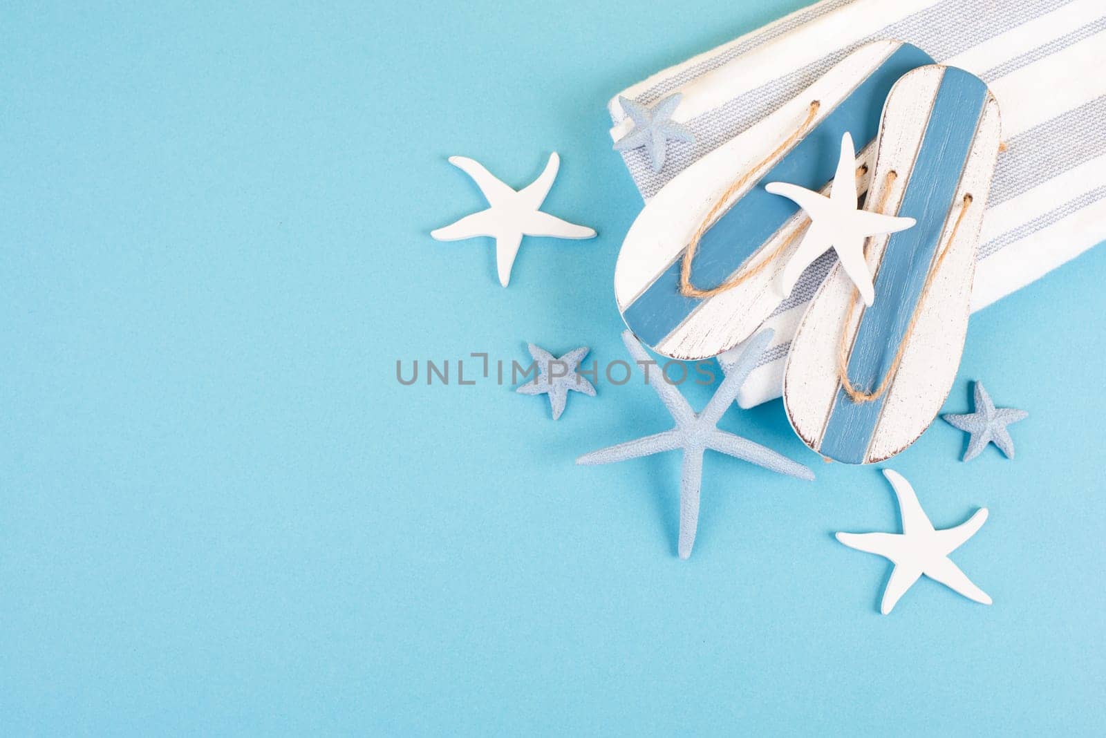 Blue colored summer and vacation background, slippers and sea stars building a frame, copy space for text, holiday and tourism concept